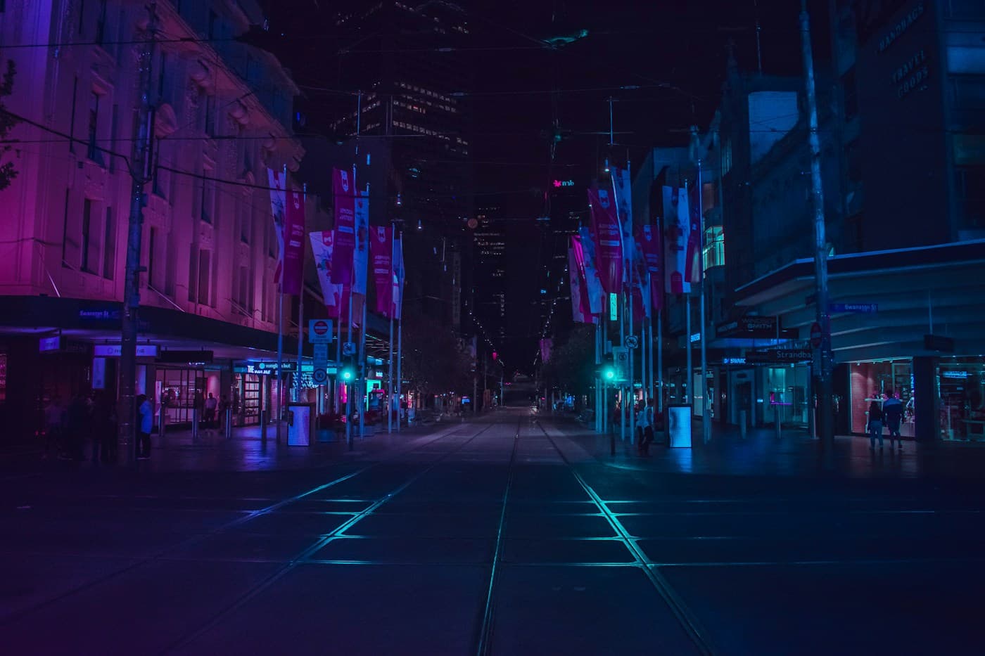 A city street and tram tracks illuminated by neon light at night